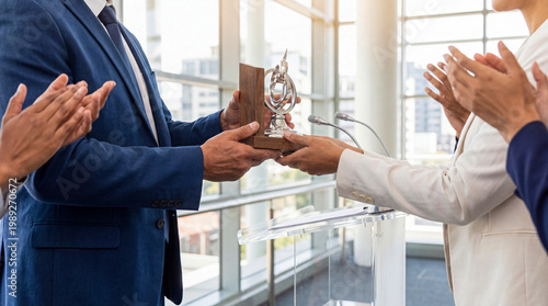 Fotografi Successful businessman receiving a modern award trophy from a speaker at a corporate event podium