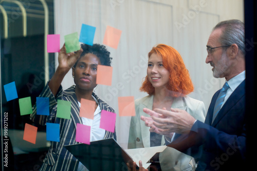 Business team brainstorming idea with sticker on glass wall for summary idea from team.