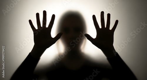 Silhouette of a person with hands pressed against a frosted glass screen.