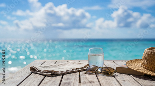 Canvastavla Serene beach day essentials on a rustic wooden table: a glass of water, stylish sunglasses, a book, and a straw hat