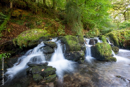 Long exposure of a waterfall on the Hoar Oak water river flowing through the woods at Watersmeet in Exmoor National Park