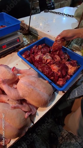 Video of a woman's hands selecting raw chicken livers and gizzards at a meat vendor's stand in a traditional market. Footage of shopping at a traditional Indonesian market in Steady 4K High Resolution