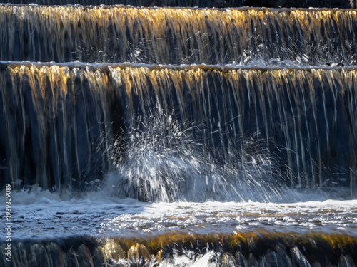Water cascades down stone steps in golden sunlight