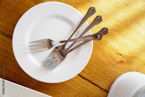 Ideas for setting a dining table,white plate set with stainless steel forks for dining on a wooden table.