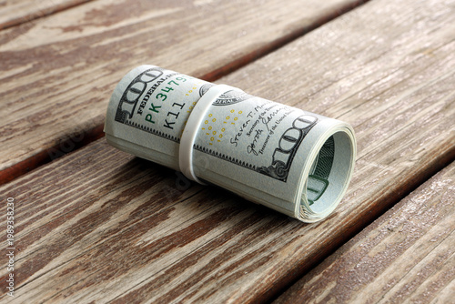 Photos Side View of Rolled US Hundred Dollar Bills on Rustic Wooden Surface