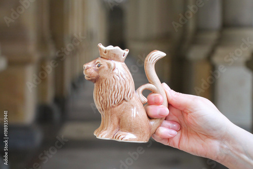 Fotografie A porcelain spa cup in the shape of a lion in a hand against the backdrop of a colonnade in the Czech Republic