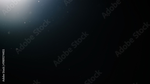 dust particles floating mid air over dark background with some lens flare