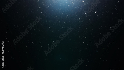 dust particles floating mid air over dark background with some lens flare