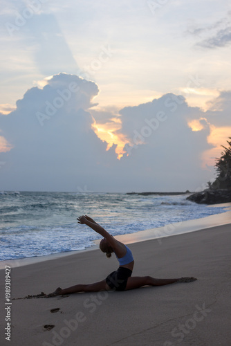 Young woman practicing yoga on beach at sunrise, stretching and flexibility training by the ocean