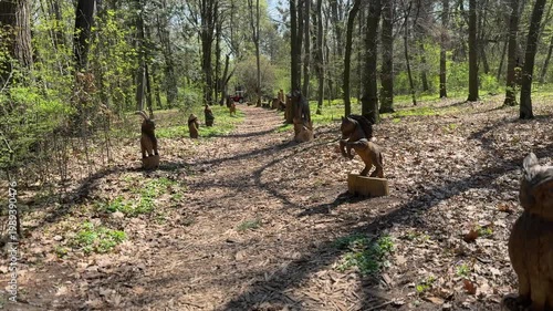 Forest trail with human sculptures along path, outdoor art and nature concept, park installation, woodland scenery, cultural landscape with copy space