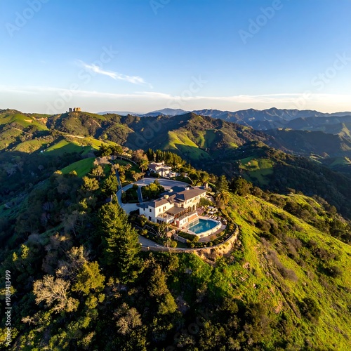 Aerial View Of A Luxury Hilltop Mansion With A Swimming Pool Perched On A Lush Green Mountain Ridge Under A Clear Blue During Golden Hour