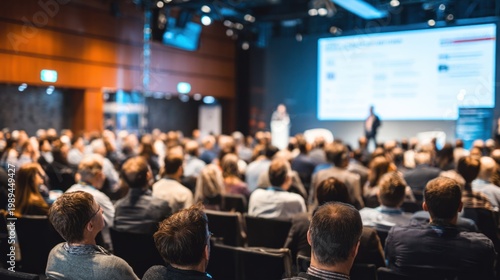 Business conference session with audience listening to presentation and large screen display in modern conference room