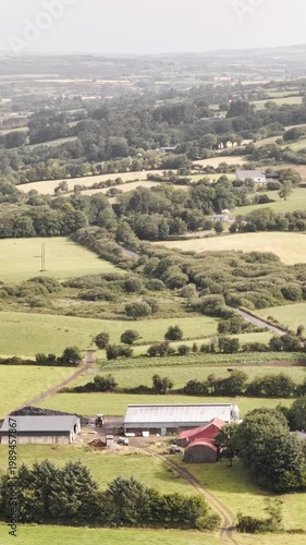 Rolling green hills define the picturesque Irish countryside featuring scattered farms and fields on a clear summer day.