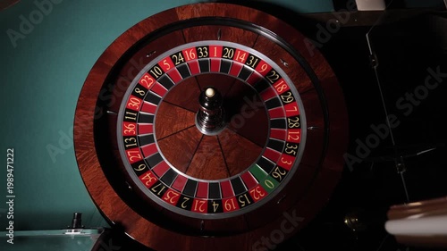 Hand spinning roulette wheel with ball in casino, close up