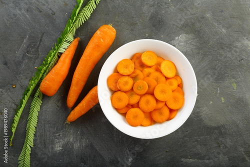 Εκτύπωση καμβά Freshly sliced carrots in a white ceramic bowl on a grey background