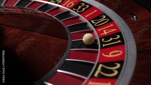Hand spinning roulette wheel with ball in casino, close up