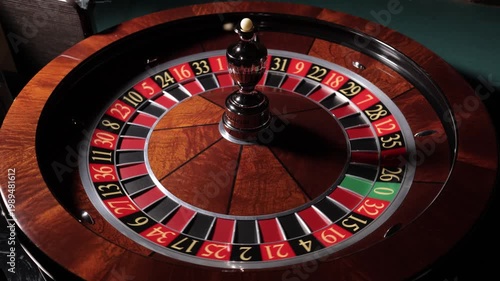 Hand spinning roulette wheel with ball in casino, close up