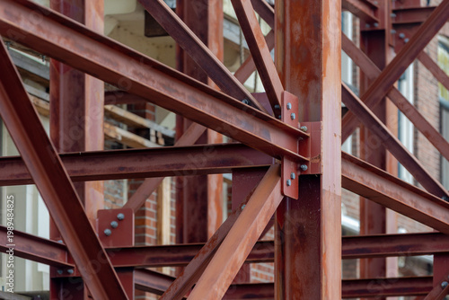 Vászonkép Building or houses renovate, Industrial construction site showing a complex network of rusted steel beams and girders, Bolted metal joints and structural framework against a brick building background