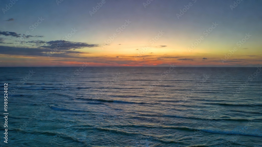 Obraz premium Sea surface reflecting pastel sunset light across horizon