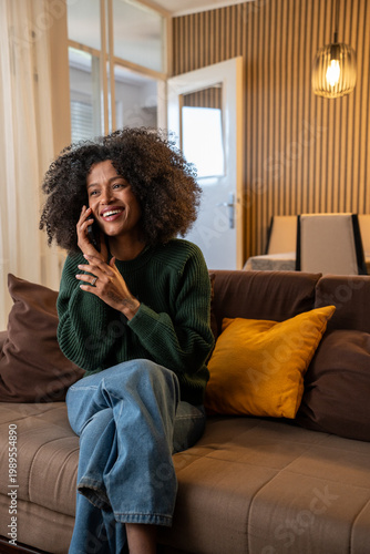 Tableau sur toile Beautiful african woman talking on phone in cozy living room at home