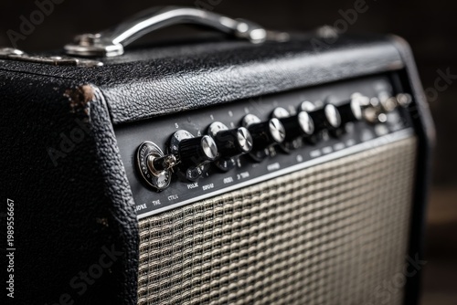 Close up of vintage guitar amplifier with control knobs and textured cover