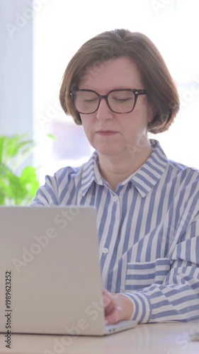 Busy Senior Woman Typing on Laptop in Office, Vertical Video