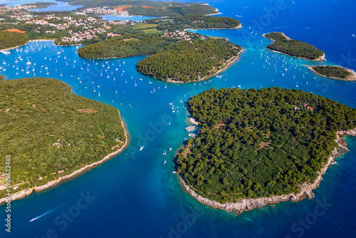 Photos Aerial view of coastal inlet with dense green forest and many anchored boats for