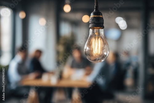 A close-up of a lit lightbulb hanging in front of an out-of-focus group of people