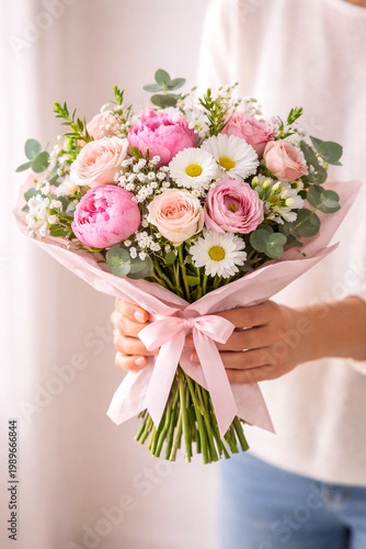 Close-up of hands holding fresh flower bouquet, Mother’s Day gift concept, soft natural light, clean neutral background.