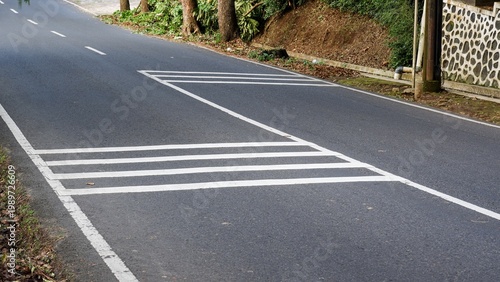 Fotografie White safety markings and rumble strips painted on a smooth asphalt road in a rural area