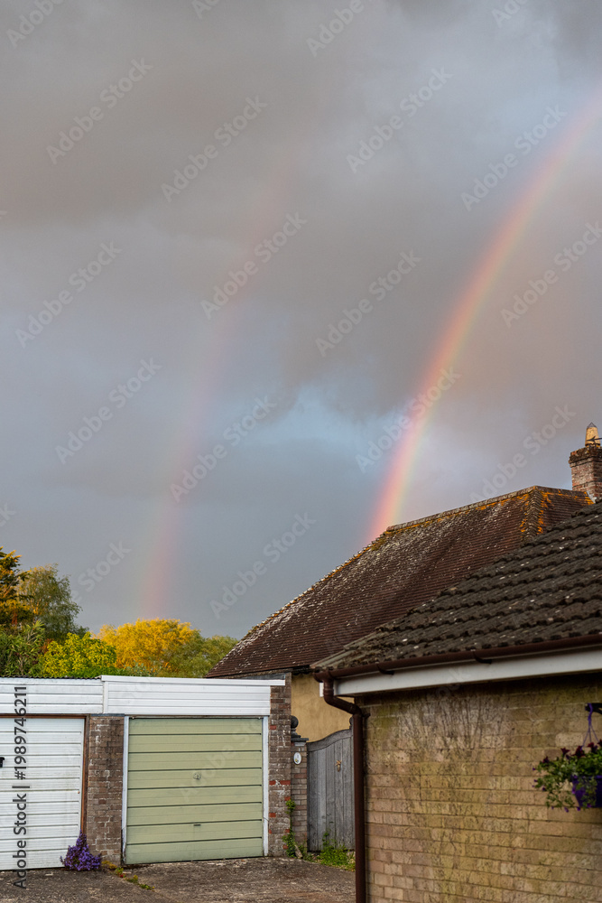 Naklejka premium A bright, colorful rainbow arcing across a dramatic cloudy sky after a rainstorm.