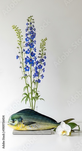 Striking still life arrangement features colorful oceanic creature balanced with tall blue blossoms and a white flower