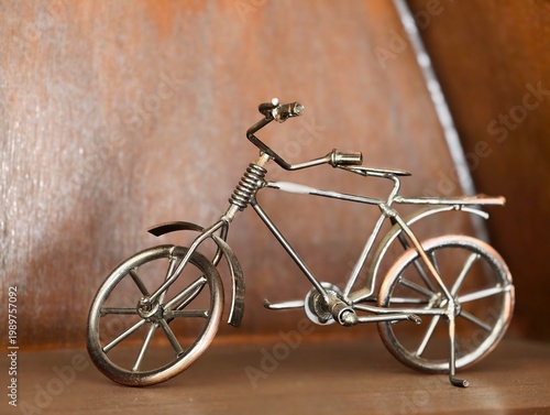 Handcrafted vintage metal bicycle miniature model featuring a rustic bronze finish and intricate welding details, isolated on a textured wooden background