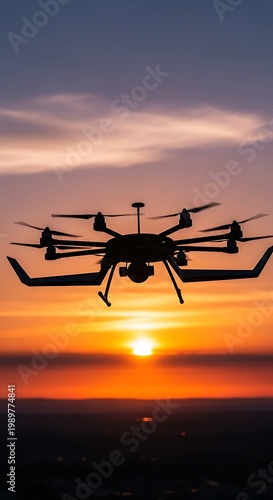 Multirotor aircraft silhouette flies against the vibrant orange and purple colors of a setting sun