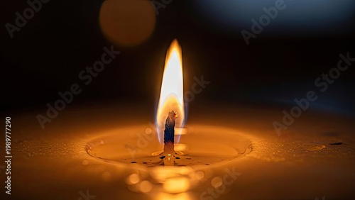 A single candle flame burns brightly in the dark