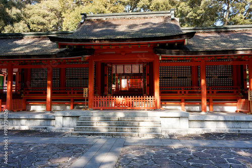 Foto Traditional Japanese Shinto shrine architecture featuring vibrant red pillars and a thatched roof at Usa Jingu