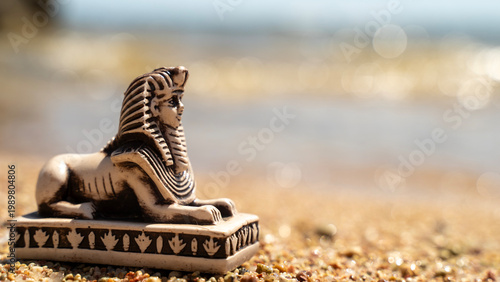 Foto Ancient sphinx statue rests on sandy shore