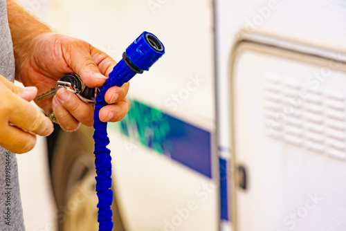 Caravan service. Hands hold hose to refilling rv water tank.