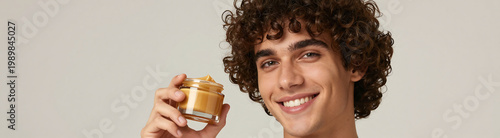 handsome hispanic young man unruly curly brown hair warm smile grasping transparent jar rich
