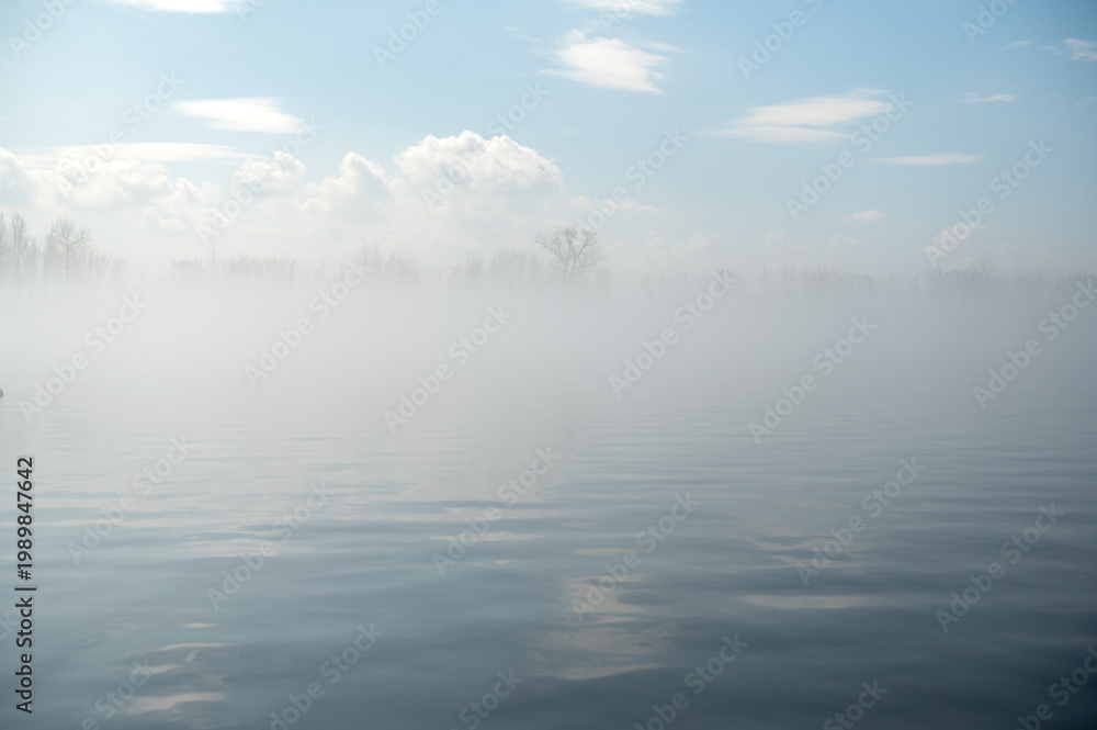 Fototapeta premium Morning fog on the river in spring. Blue sky with clouds.
