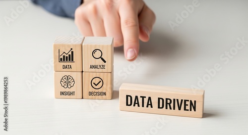 Hand pointing to wooden blocks illustrating data analysis process: data, analyze, insight, decision, and a separate block labeled 'DATA DRIVEN'.