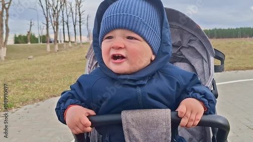 Cute toddler boy smiling in stroller during outdoor walk