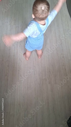 Joyful toddler boy spinning around happily