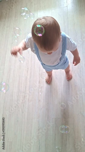 Toddler boy looking up and catching soap bubbles