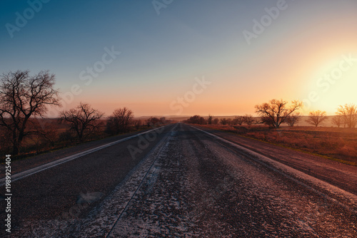 Empty asphalt road leading to horizon at sunset in rural landscape