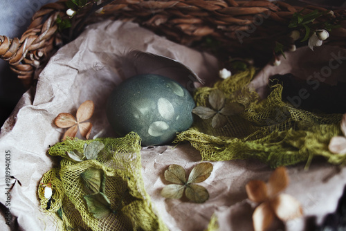Natural Easter decoration with dried petals, colored eggs, craft paper, and rustic wicker basket