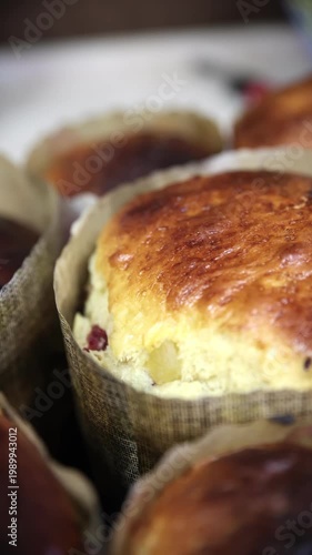 Detailed close-up of a freshly baked traditional Easter kulich with a glossy golden-brown crust and visible raisins. Baked in a paper form, showing beautiful texture and homemade quality. 