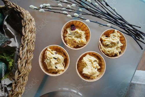 Raw dough with raisins for cooking easter cakes in molds, pussy willow twigs, colored eggs in the basket