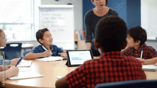 A dynamic wide video of diverse students (6-10) with their teacher in a modern, brightly lit classroom, engaged in collaborative learning via smooth tracking and close-ups, bright natural daylight,