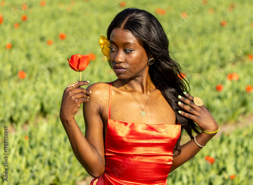 Elegant Young Woman in Red Dress Holding Tulip in Flower Field